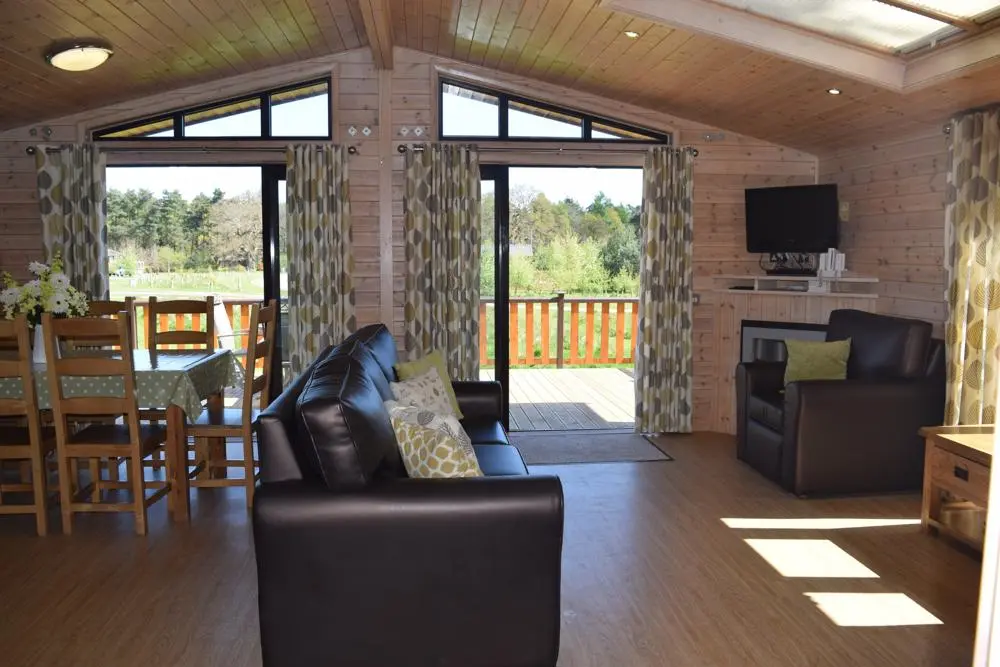 The Activities Unlimited Short Breaks Lodge open plan living room with leather sofas, dining table and flat screen TV.