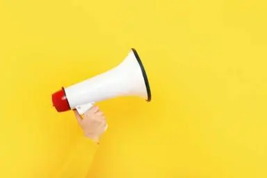 A person holding a white megaphone on a yellow background